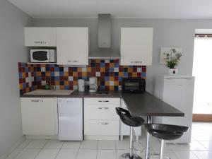 a kitchen with white cabinets and a black counter top at Gite Chez Santou in Rocamadour +14 photos
