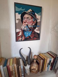 a painting of a cowboy on a wall with books at Thali Thali Game Lodge in Langebaan