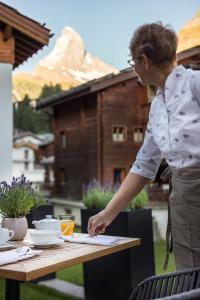 a woman standing at a table writing on a paper at Europe Hotel & Spa in Zermatt