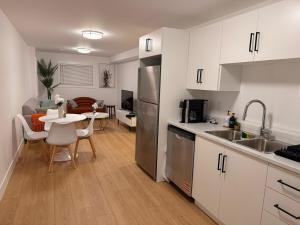 a kitchen with white cabinets and a small table with chairs at Modern 2BR Suite, Wifi, Workstation and Comfy Beds in St. John's