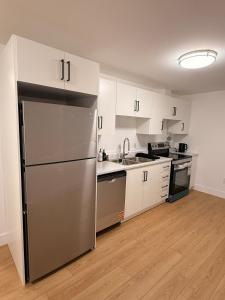 a kitchen with a stainless steel refrigerator and white cabinets at Modern 2BR Suite, Wifi, Workstation and Comfy Beds in St. John's +17 photos