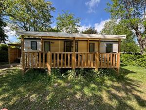 a small yellow house with a wooden deck at Flower Camping Les Mijeannes in Rieux-de-Pelleport