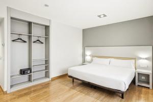 a bedroom with a white bed and shelves at B&B HOTEL Logroño Las Cañas in Viana