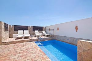 a swimming pool with white chairs and a swimming pool at South Star Guesthouse in Quelfes