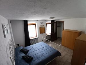 a bedroom with a blue bed and two windows at Nonna Lidie in Aymavilles