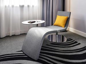 a chair with a yellow pillow and a table at Novotel York Centre in York +158 photos