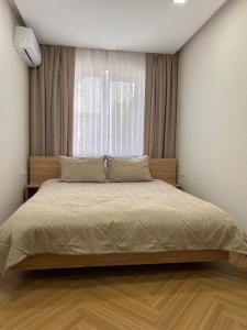 a bedroom with a large bed in front of a window at Modern Apt in Shymkent