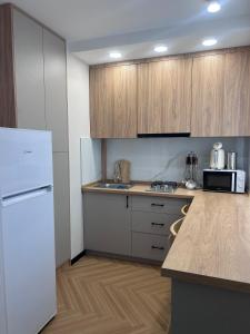 a kitchen with a white refrigerator and wooden cabinets at Modern Apt in Shymkent