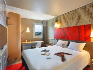 a hotel room with a large bed with two ties on it at Ibis Le Havre Sud Harfleur in Harfleur