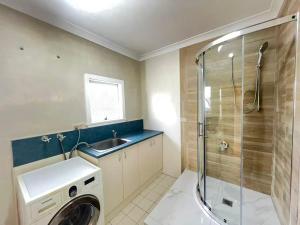 a bathroom with a sink and a washing machine at Room 78 in Merrylands