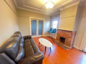 a living room with a leather couch and a fireplace at Room 78 in Merrylands