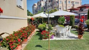 a garden with flowers and tables and an umbrella at Villa Marija in Struga