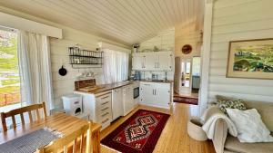a kitchen with white cabinets and a table and a couch at Atlantic Shoreline Cabin in Vestvågøya