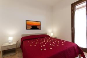 a bedroom with a bed with a red bedspread with flowers on it at Appartamenti Elios in Birgi Vecchi