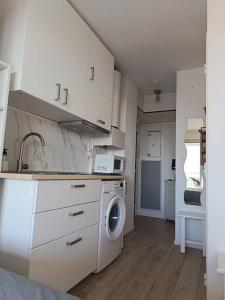 a kitchen with white cabinets and a washing machine at studio cabine vue sur mer in Sète +17 photos