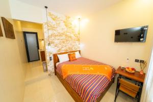 a small room with a bed and a desk and a tv at Casa Seraya Dalung in Dalung