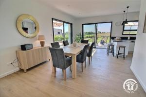 a dining room with a wooden table and chairs at Enez bihan in Plougrescant
