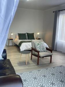 a bedroom with a bed and a chair and a couch at Net Dankbaar in De Kelders