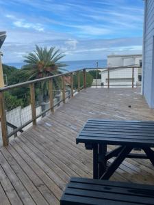 a wooden deck with a picnic table on a balcony at Net Dankbaar in De Kelders +1 photo