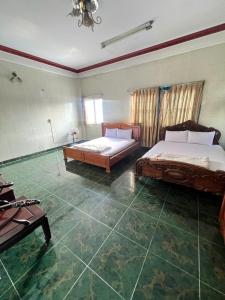 a large room with two beds and a table at Khách Sạn Vũ Nam Hưng in Ấp Hưng Lộc