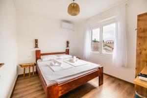 a bedroom with a bed with white sheets and a window at Late Story in Podgorica