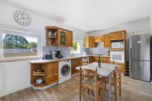 a kitchen with a table and a clock on the wall at Gite cap 3KM plages in Telgruc-sur-Mer