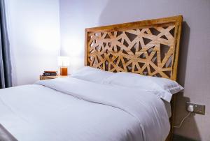 a bedroom with a white bed with a wooden headboard at Apartment in Tilisi in Gatimu