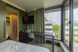 a hotel room with a desk and a large window at Green Hotel in Genk +59 photos