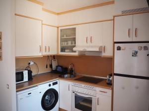 a kitchen with white cabinets and a washer at Fuerte Wave House in Lajares