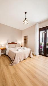 a white bedroom with a large bed and a wooden floor at Casa Eloah in Antequera