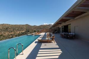 a swimming pool with chairs and tables on a building at Elysium Caved Villas - Carved From Calm by etouri in Heraklio