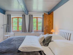 a bedroom with a large bed and two windows at Reetdachhaus Silvi in Schwabstedt