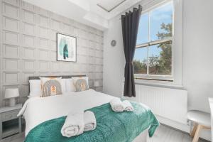 a white bedroom with a bed and a window at The Cozy Stays Hackney House in London