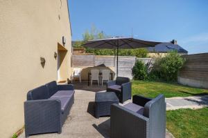 a patio with chairs and an umbrella and a table at Gite Dune 3km plage in Telgruc-sur-Mer