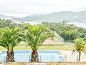 two palm trees in front of a swimming pool at Apartamento MN Estorde by ALÔGA in Vilar