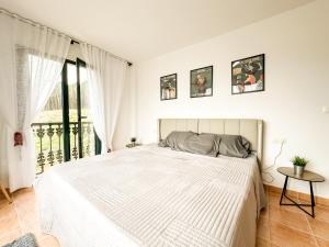 a white bedroom with a large bed and a window at Apartamento MN Estorde by ALÔGA in Vilar +7 photos