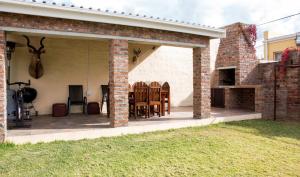 an outdoor patio with chairs and a fireplace at Protea House in Graaff-Reinet