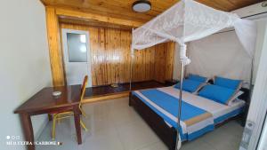 a bedroom with a bed with an umbrella and a desk at Forest Hotel in Miarinarivo +7 photos