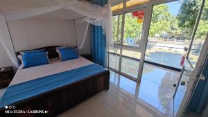 a bedroom with a bed with blue pillows and a window at Forest Hotel in Miarinarivo