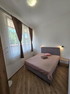 a bedroom with a bed and two windows at Villa Iper Krystallos in Budva +4 photos