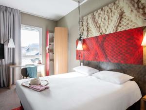 a bedroom with a large white bed with a red headboard at ibis Saint Malo Plage in Saint Malo