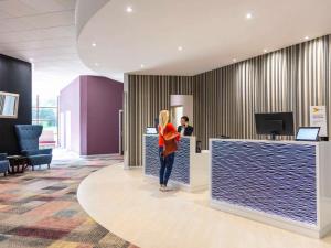 a woman standing at a counter in an office at Novotel Newcastle Airport in Newcastle upon Tyne