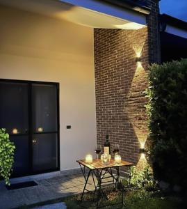 a table with candles and wine bottles on a brick wall at Feel B&B and more in Saluzzo