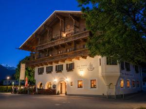 a large white building with a wooden roof at Landhotel Kaserer in Bramberg am Wildkogel