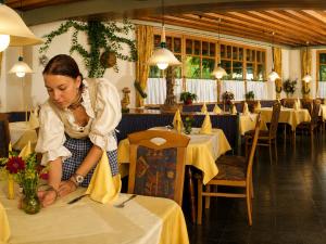 a woman is sitting at a table in a restaurant at Landhotel Kaserer in Bramberg am Wildkogel