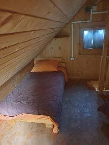 a bed in a wooden cabin with a window at Apartma Vidmar Otlica in Ajdovščina