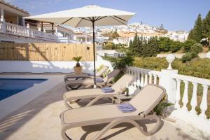 a group of chairs and an umbrella on a balcony at Rd02 La Casa Hermosa in Torrox