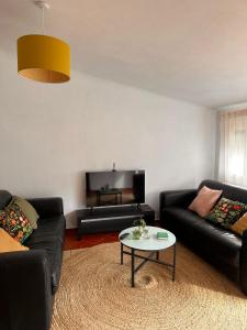 a living room with two black couches and a table at Lake House Gerês in Admeus