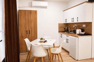 a kitchen with a white table and white chairs at Kalinovi Apartments in Gevgelija