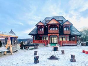 a large house in the snow with a picnic table at Casa Moroseneasca Breb in Breb